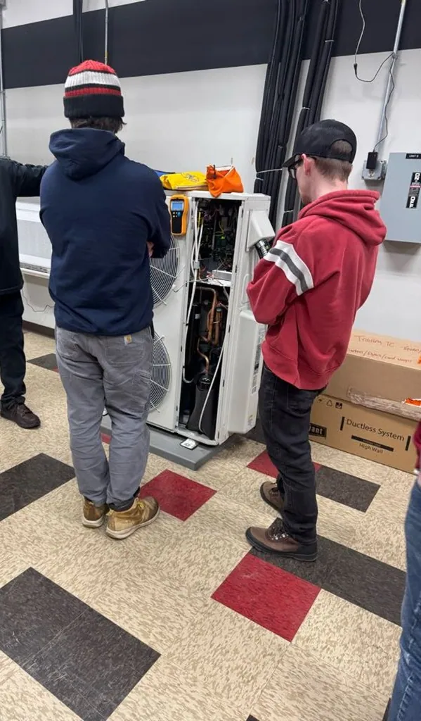 Technicians examining the internal components of a Bryant ductless mini-split unit