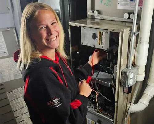 A Mankato Heating & Cooling technician servicing an open Bryant furnace